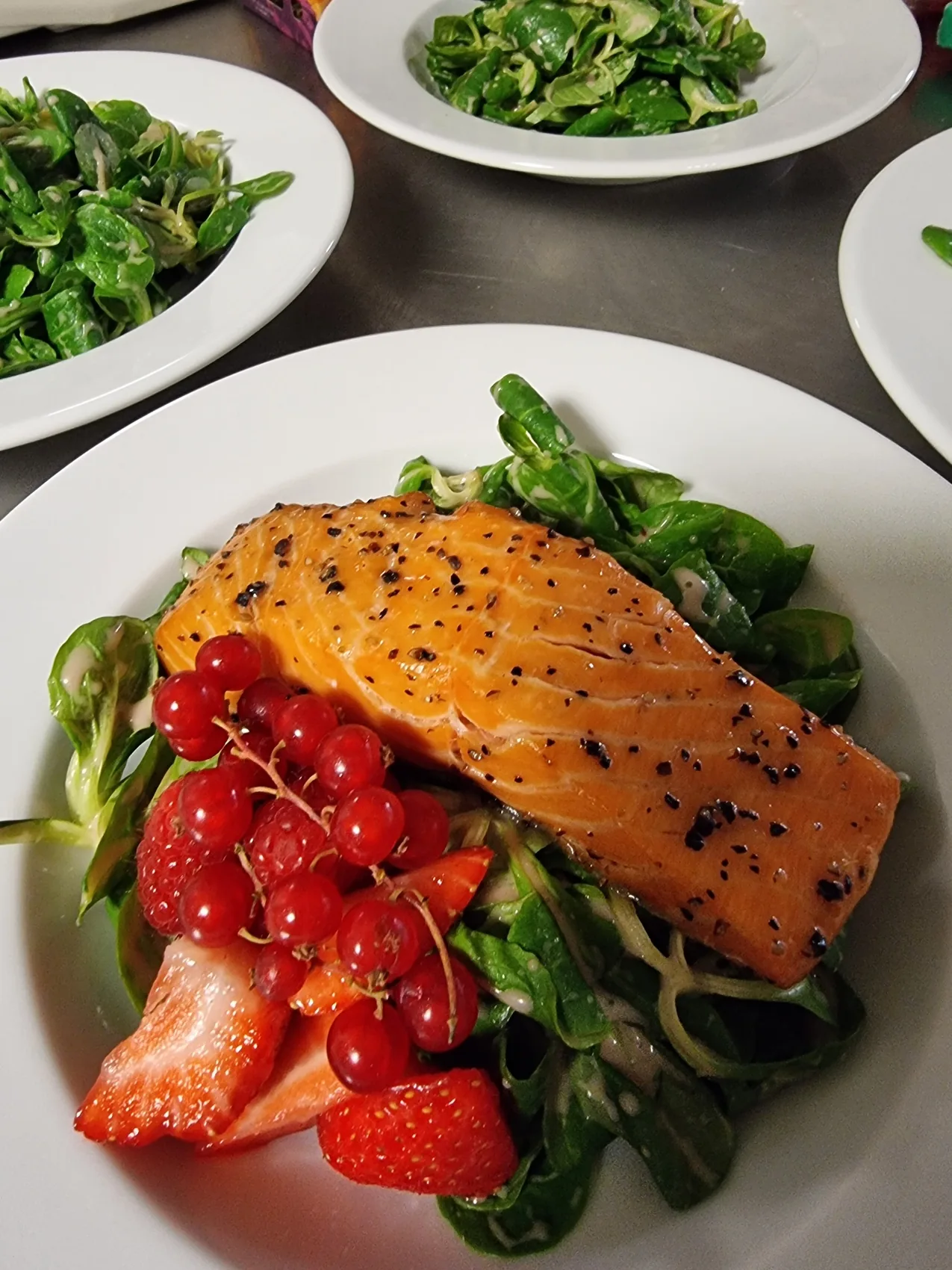 Fein angerichtetes Lachsgericht mit Salat und frischen Beeren
